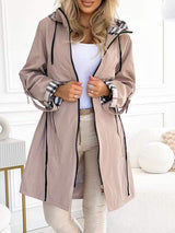 Beige trenchcoat met ruitvoering in de capuchon en manchetten.