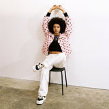 roze jas met stippen model zittend op stoel fashion outfit
